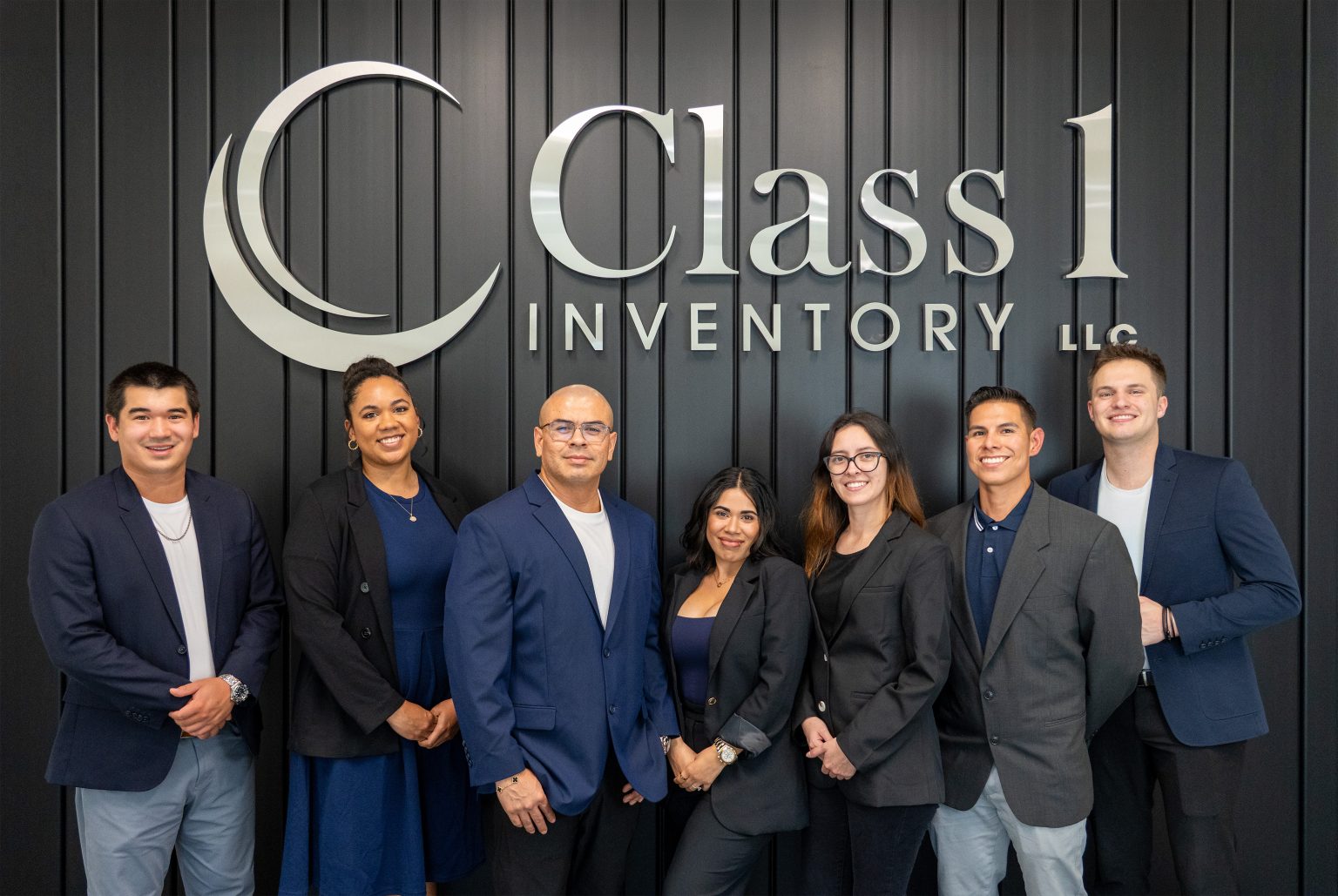 The Class 1 Inventory team in front of the company logo at the Southlake, Texas office